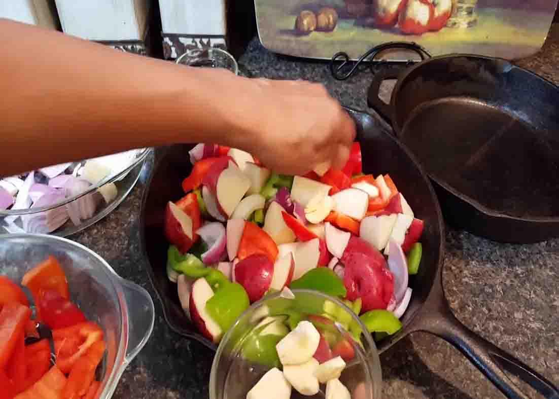 Adding all the ingredients in the pan for the roasted sausage and peppers recipe