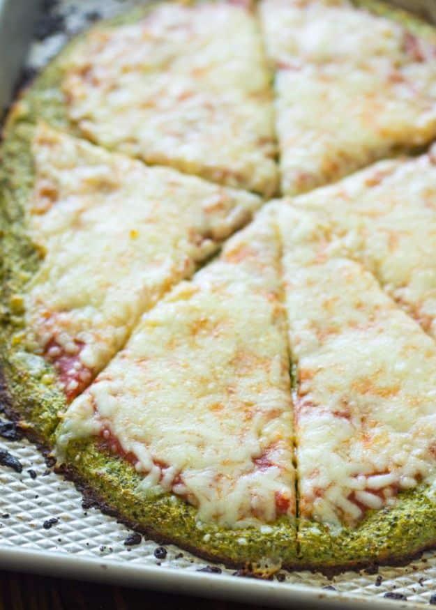 Broccoli crust pizza sliced on a metal pan, green flecked crust under tomato sauce and browned melted mozzarella