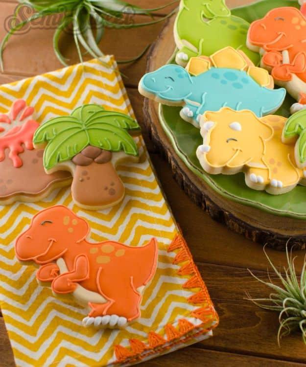 T-Rex dinosaur cookies decorated in royal icing, outlined and flooded in sections as green dinosaur shapes