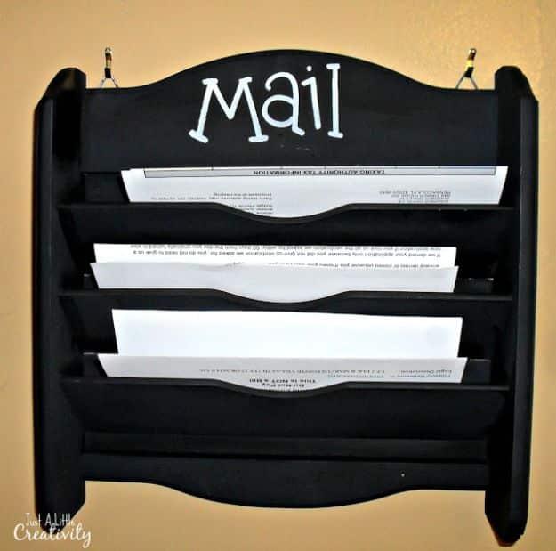 Black painted wooden wall mail rack with four slots holding envelopes, white lettering across the arched top