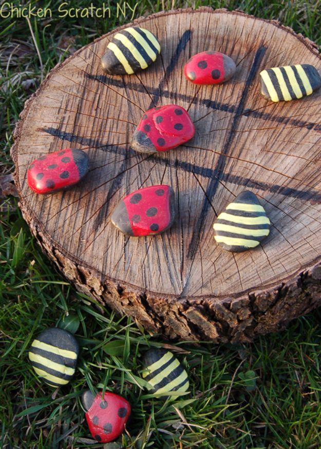 Spring tic tac toe game on a log slice with painted river rocks made to look like red ladybugs and yellow bees