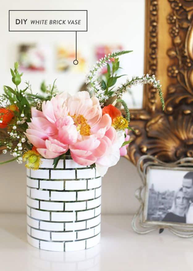 DIY white brick vase, a glass cylinder painted white in a brick pattern holding a large pink peony and small blooms
