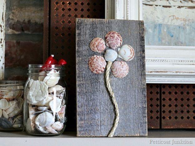 Seashell flower art, a flower of pink and grey shells glued to reclaimed wood with a sisal rope stem