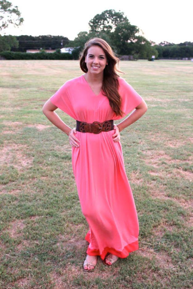 Woman standing on grass in a bright coral jersey maxi dress cinched with a wide brown leather waist belt