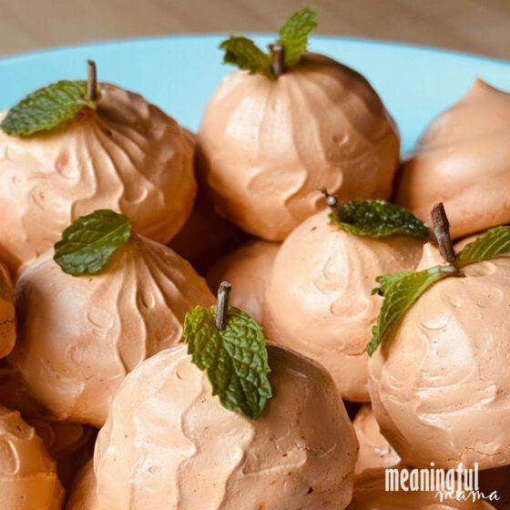 Orange pumpkin-shaped meringue cookies piped with ridges and finished with small green stems for Halloween