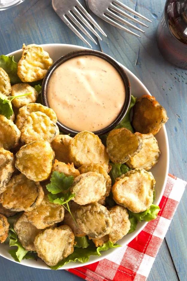Copycat Texas Roadhouse fried pickles, golden battered pickle slices piled beside a creamy dipping sauce