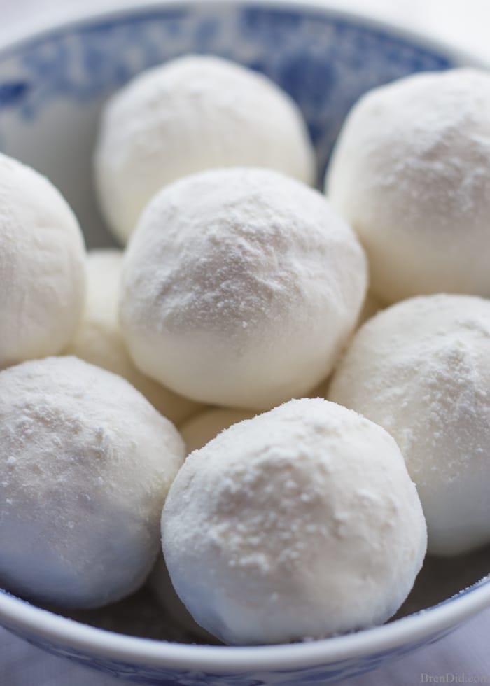 Bowl of round snowy white bath melts dusted in powdered milk, sitting on a blue and white patterned china dish