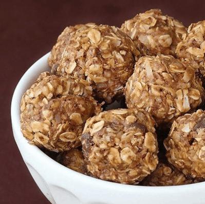 No bake oatmeal energy bites rolled into balls with visible oats and coconut flakes piled in a white bowl