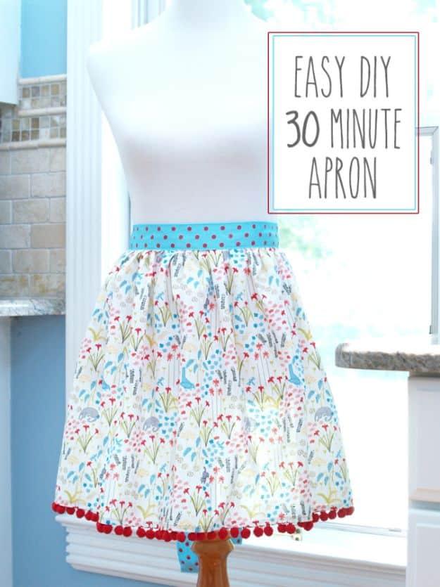 A cotton apron with a deep front pocket and long wrap ties, hanging over the back of a kitchen chair.
