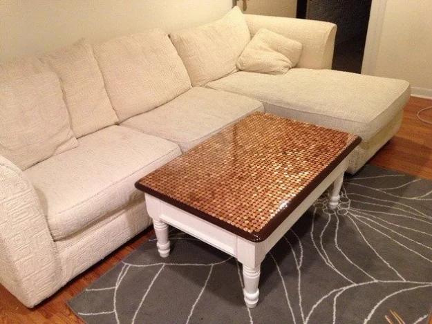 Penny top coffee table with white turned legs and a glossy copper coin surface, in front of a cream sectional