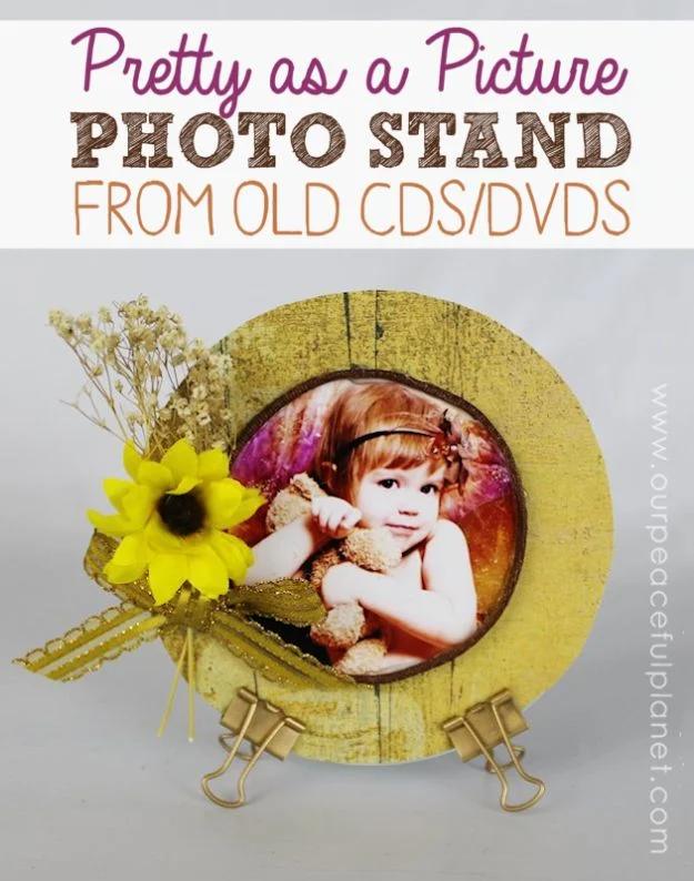 Photo stand made from an old CD covered in yellow patterned paper, standing on two gold binder clip feet