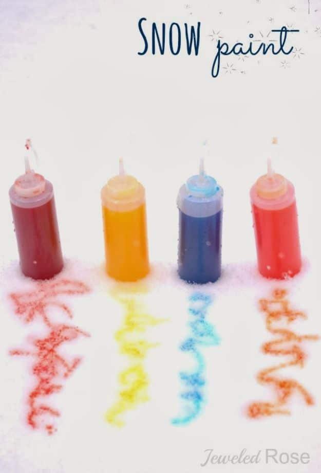 Four squirt bottles of red, yellow, blue and orange liquid above matching squiggles painted onto white snow