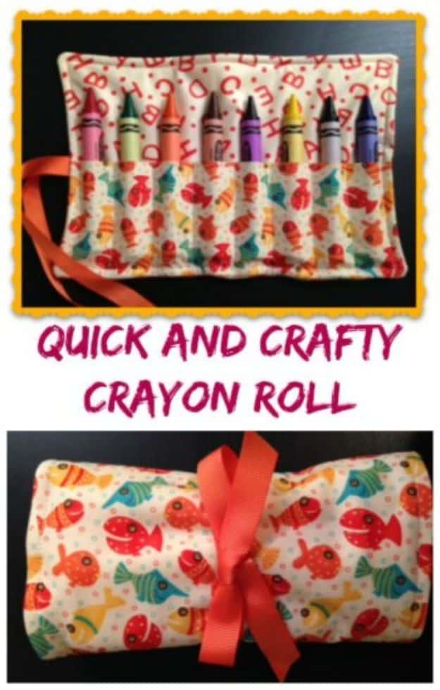 A cotton crayon roll opened flat to show stitched slots filled with crayons, ribbon tie trailing across a wooden table