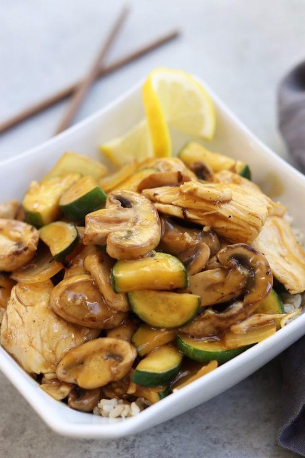 Lemon chicken stir fry with zucchini, mushrooms and sweet onion in a bright citrus sauce over rice ready to serve at home