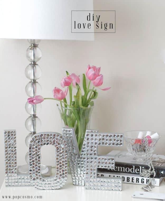 Silver sequin covered LOVE letters standing on a dresser beside pink tulips and a stack of magazines
