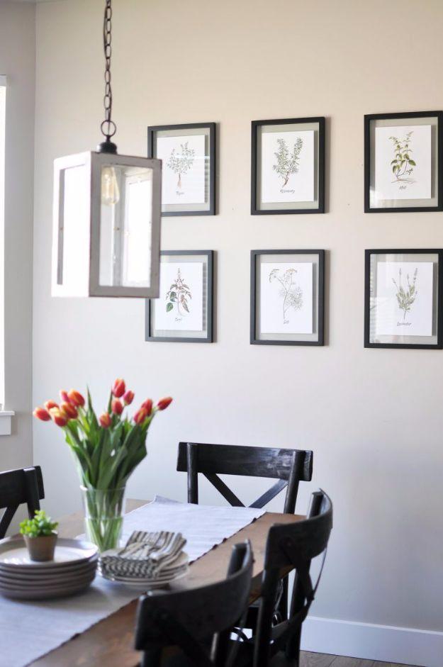 Six botanical herb printables in black floating frames hung in a grid above a dining table with tulips