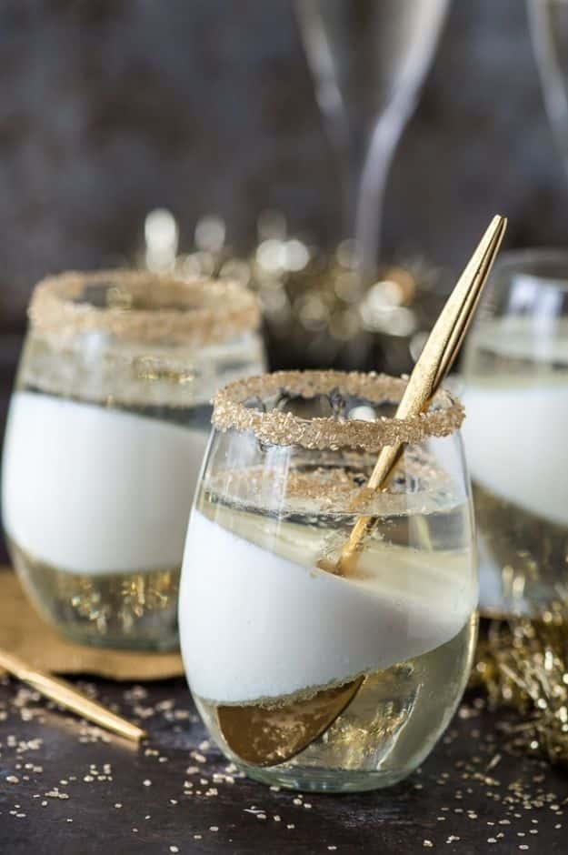 Champagne jello cups layered in glasses with a white condensed milk layer and gold sugar around the rim