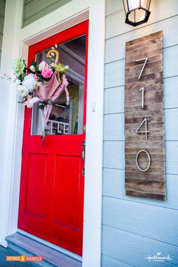 DIY house number sign made from stained paint sticks on plywood with white numbers, beside a red door