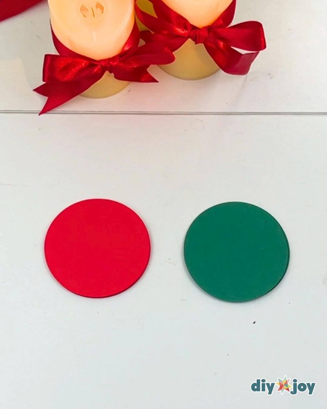 Kids Crafts - one red and one green paper circle sitting on a white table below two ribbon tied candles