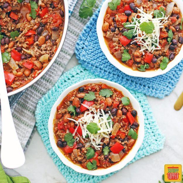 Ground beef chili with pinto beans, black beans and diced tomatoes topped with shredded cheese and cilantro