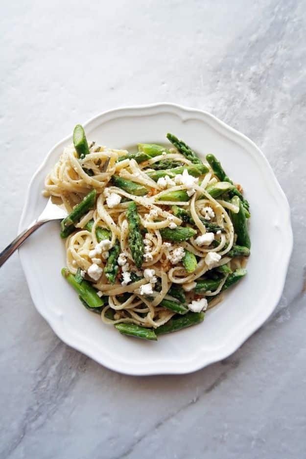 Lemon feta linguine with garlic asparagus on a white plate, pasta twirled with green spears and feta