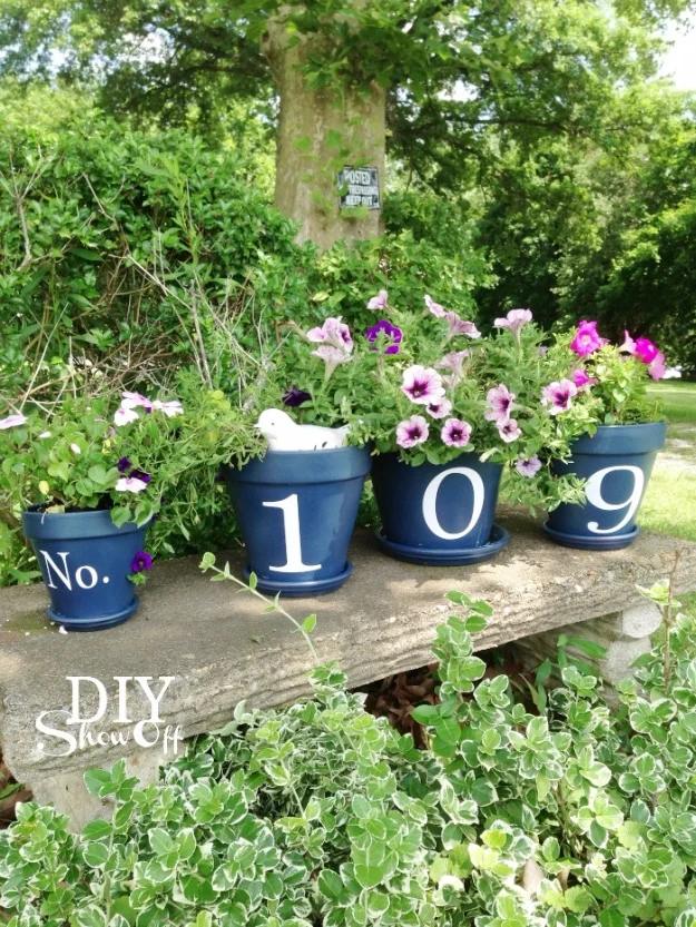 DIY curb appeal house number flower pots painted navy with white numerals and pink petunias on a weathered garden bench