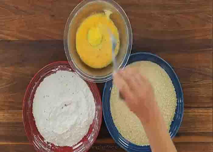 Coating the slices of zucchini with flour, egg, and bread crumbs