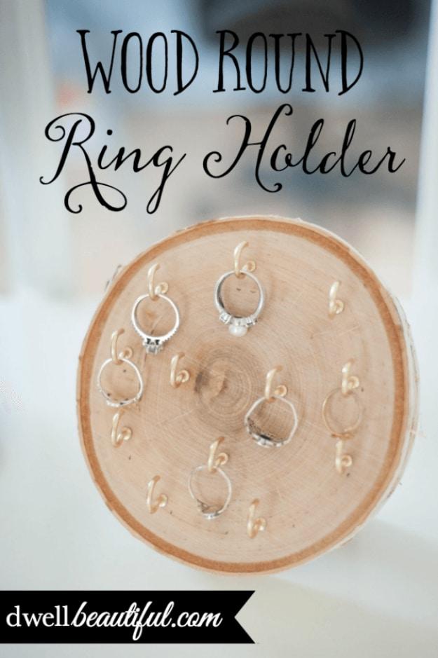 DIY wood ring holder, a pale sliced tree round standing on a dresser with small gold hooks holding silver rings