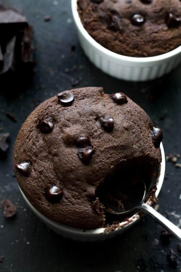 Fudgy double chocolate mug cake baked in a white ramekin with chocolate chips on top and a spoon dug into it