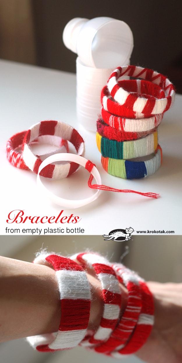 Stacked bracelets made from plastic bottle rings wrapped in red and white yarn, with a cut bottle alongside
