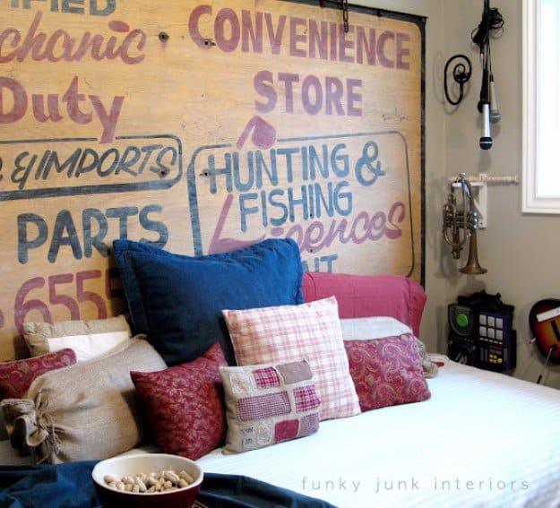Vintage sign headboard, a weathered wooden store sign lettered in red and blue above navy and red pillows