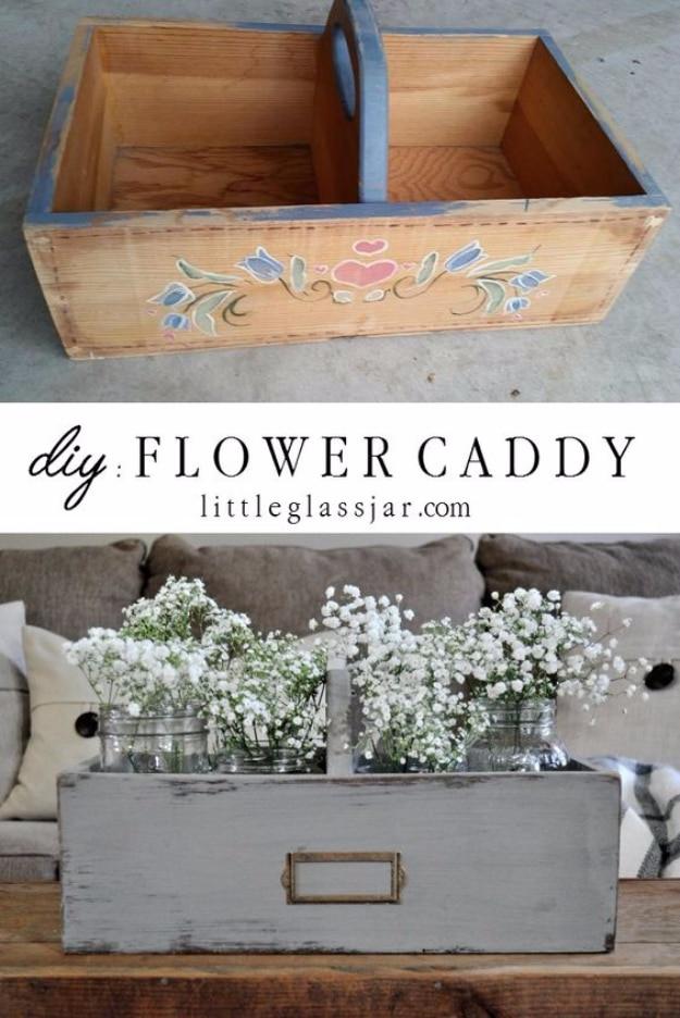 Grey painted wooden caddy with a brass label plate holding four glass jars of white baby's breath on a coffee table