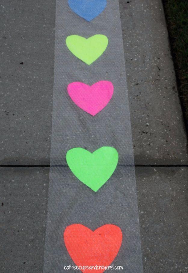 Valentine hop and pop game with paper hearts taped under bubble wrap on the floor for children to jump on