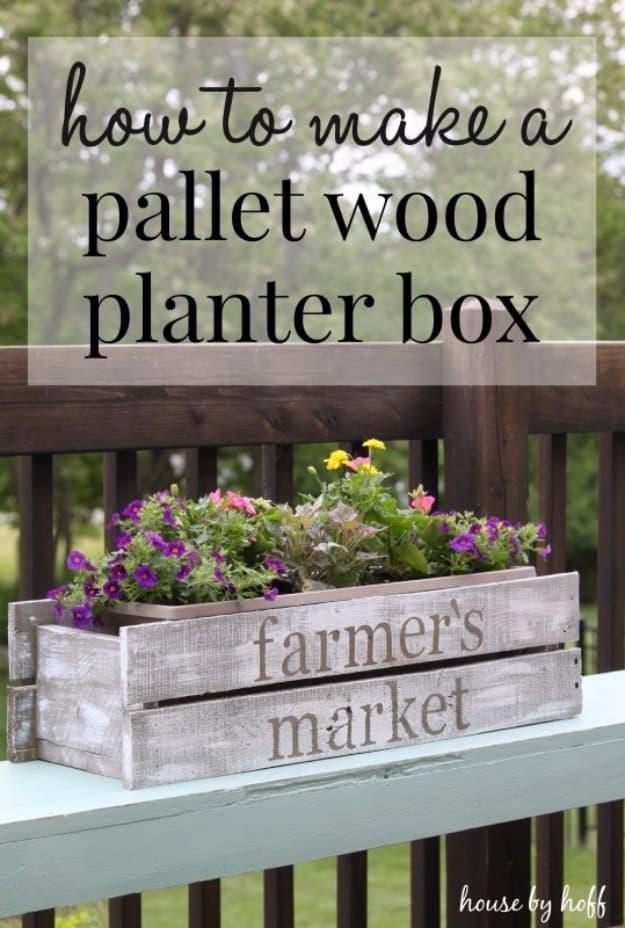 A planter box made from weathered pallet boards sits on a porch step, filled with soil and young herb seedlings