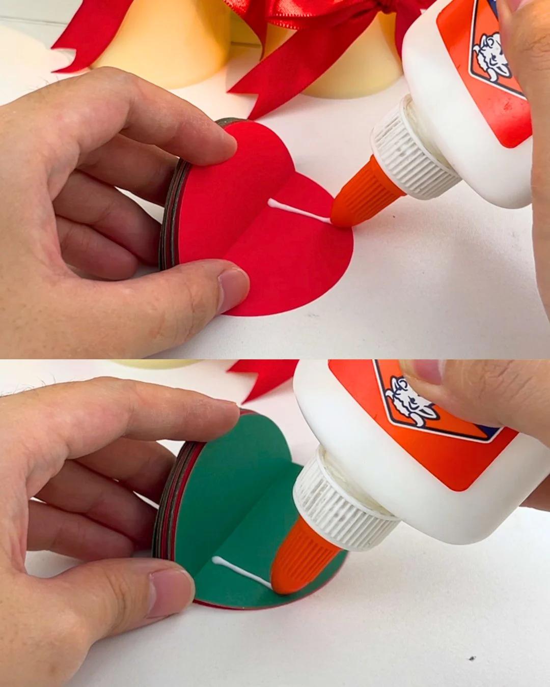 Christmas Decorations - white craft glue being applied along the folded edge of a red paper half circle and then a green one