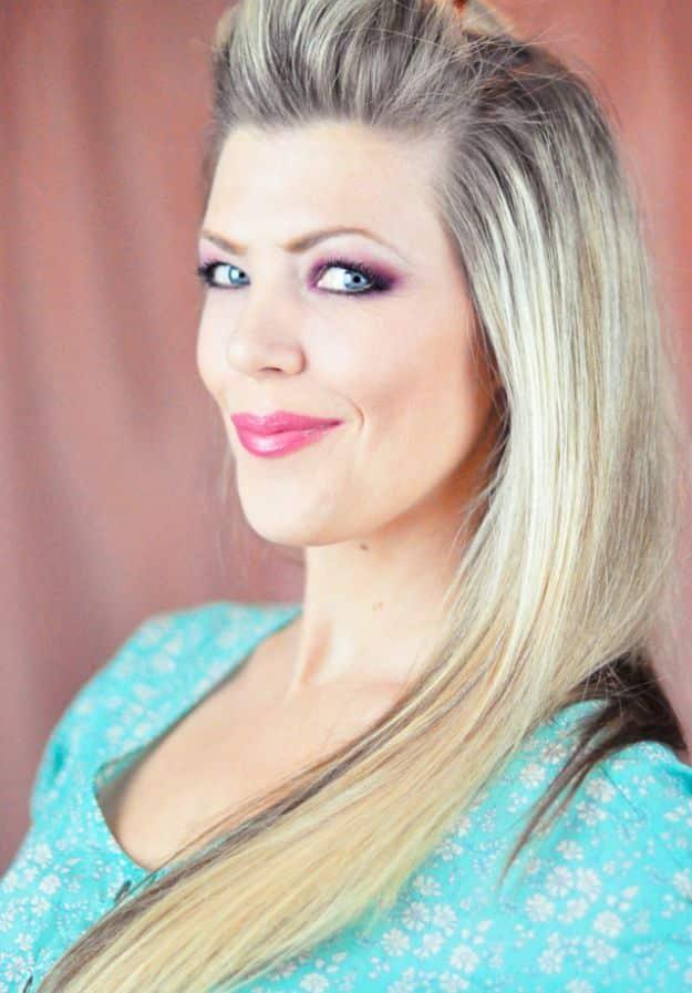 Frozen Elsa Halloween makeup with purple shadow, pink lips, a long blonde braid and a sparkling blue dress