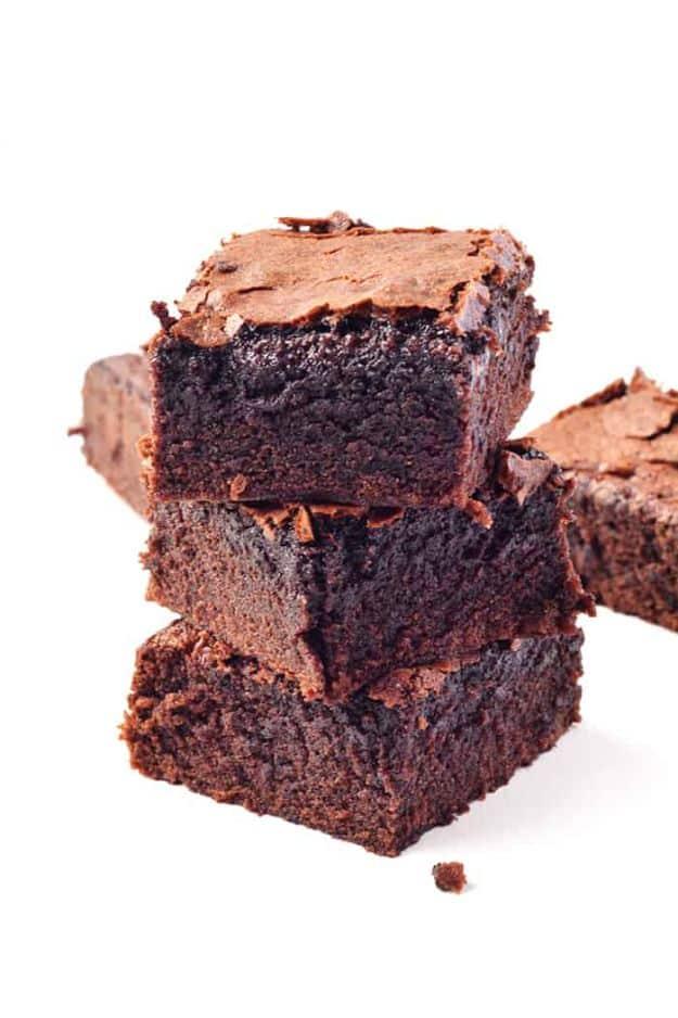 Easy one bowl cocoa brownies stacked on a white surface with crisp tops and a soft chewy chocolate crumb