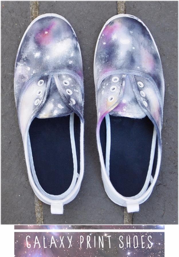 Galaxy print shoes graphic, a pair of white canvas sneakers dyed in purple and blue galaxy patterns on gray concrete