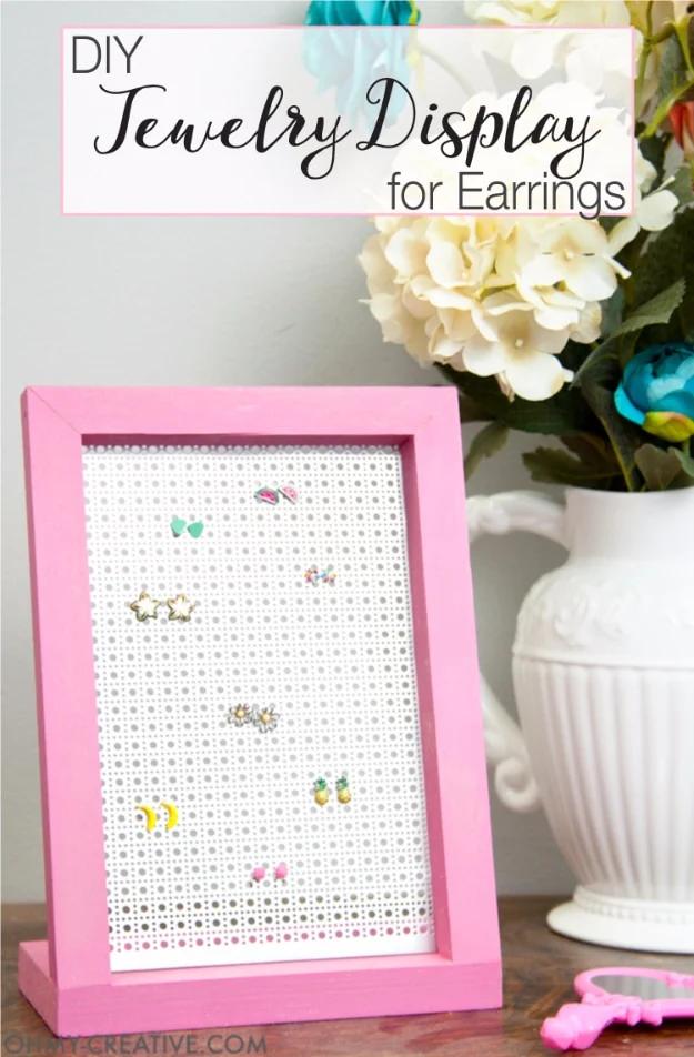 DIY jewelry display for earrings, a pink wooden frame holding perforated metal sheet with small stud earrings pushed through