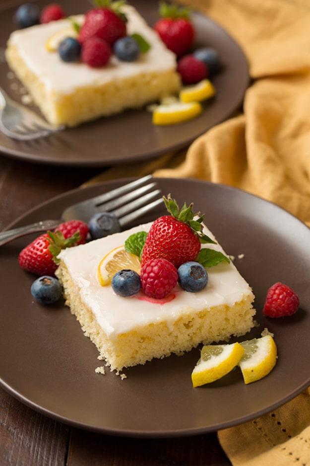Lemon sheet cake squares with white glaze topped with fresh strawberries, raspberries and blueberries