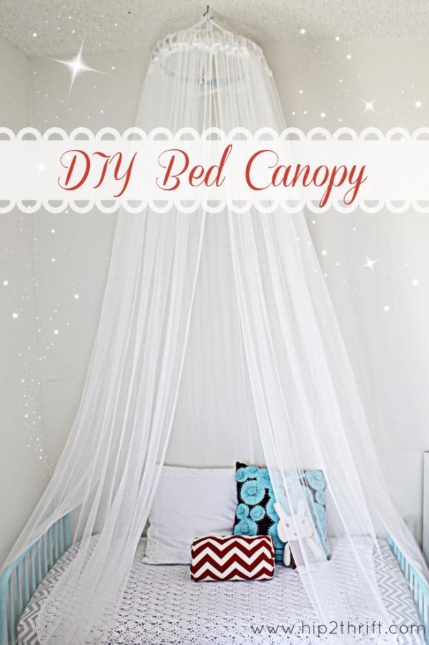 White sheer bed canopy hanging from a hoop over a small bed with turquoise rails, white lace cover and a red chevron pillow