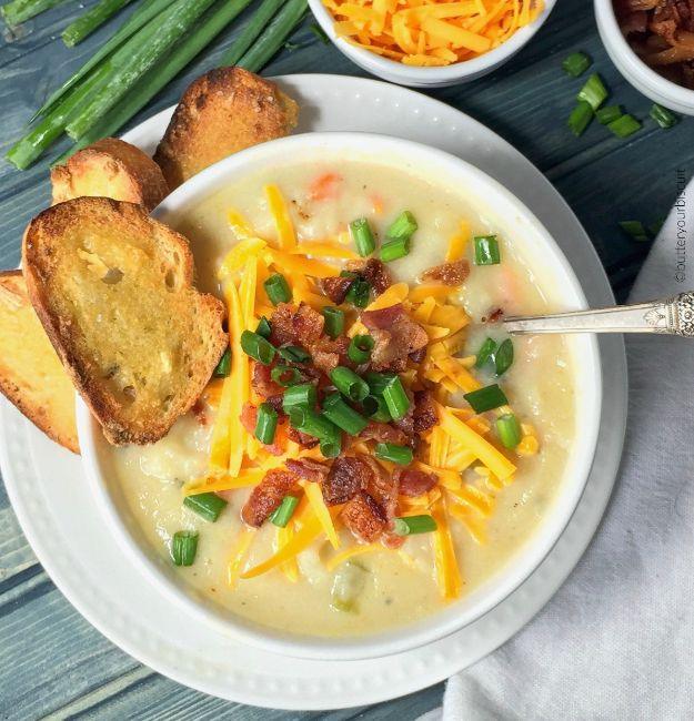 Loaded potato soup in a white bowl with shredded cheddar, bacon, green onion and toasted bread slices