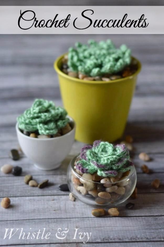 A crocheted green succulent in two shades of yarn, potted with small stones in a white dollar store pot