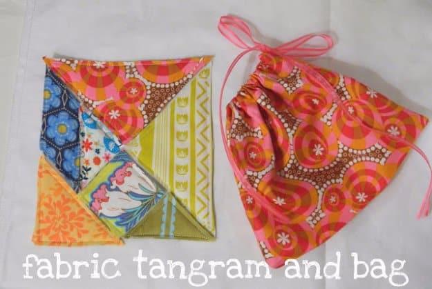 Seven fabric tangram puzzle pieces in bright floral and geometric prints beside a matching drawstring bag with pink ribbon