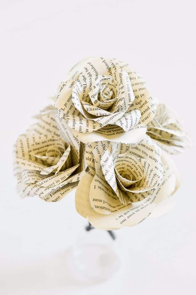 Bouquet of roses folded from printed book pages arranged in a small white vase against a pale background