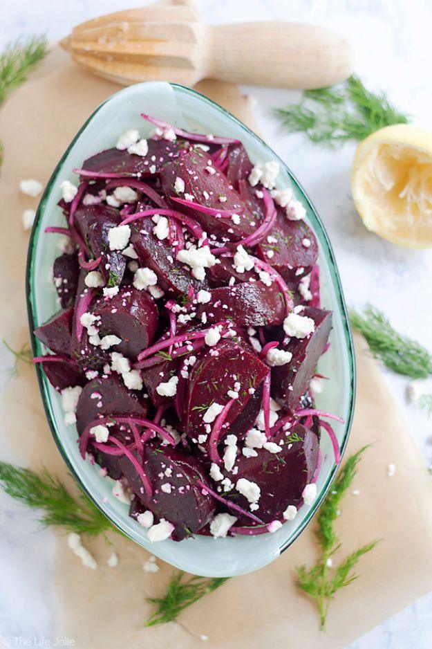 Roasted beet salad with crumbled feta cheese, fresh dill and thin red onion slices in a white serving bowl