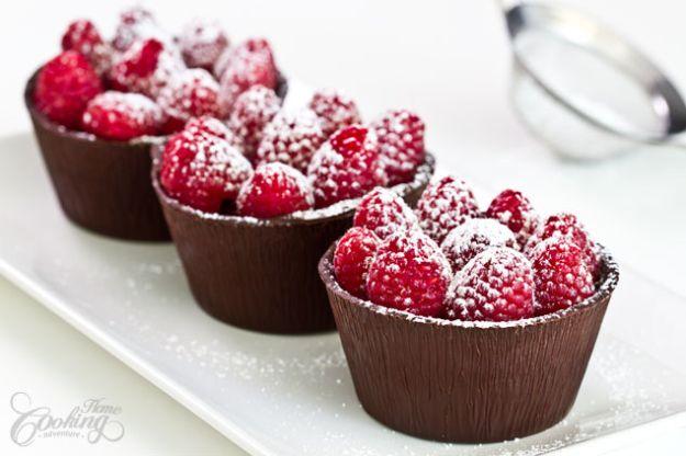 Raspberry chocolate cups with dark chocolate shells packed with fresh raspberries and dusted with sugar