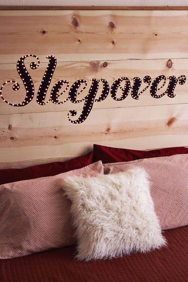 DIY light up headboard, a pale pine plank headboard with a word in cursive outlined by small warm bulb lights
