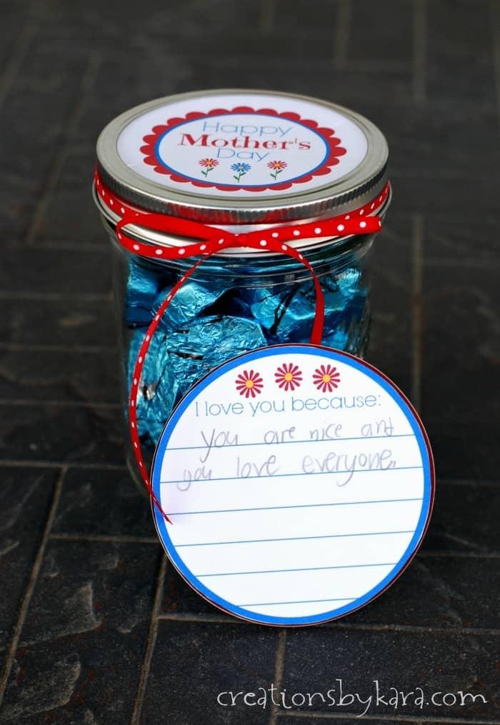 Mason jar filled with foil wrapped chocolates and small folded paper notes, tied with ribbon and a gift tag