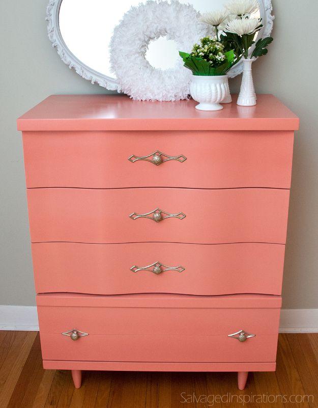 Coral painted dresser with wave shaped drawer fronts and ornate silver pulls, white oval mirror and milk glass vases above